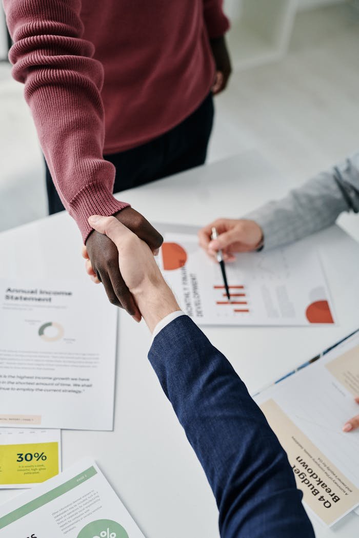 Professional handshake over financial documents symbolizes successful business partnership and teamwork.