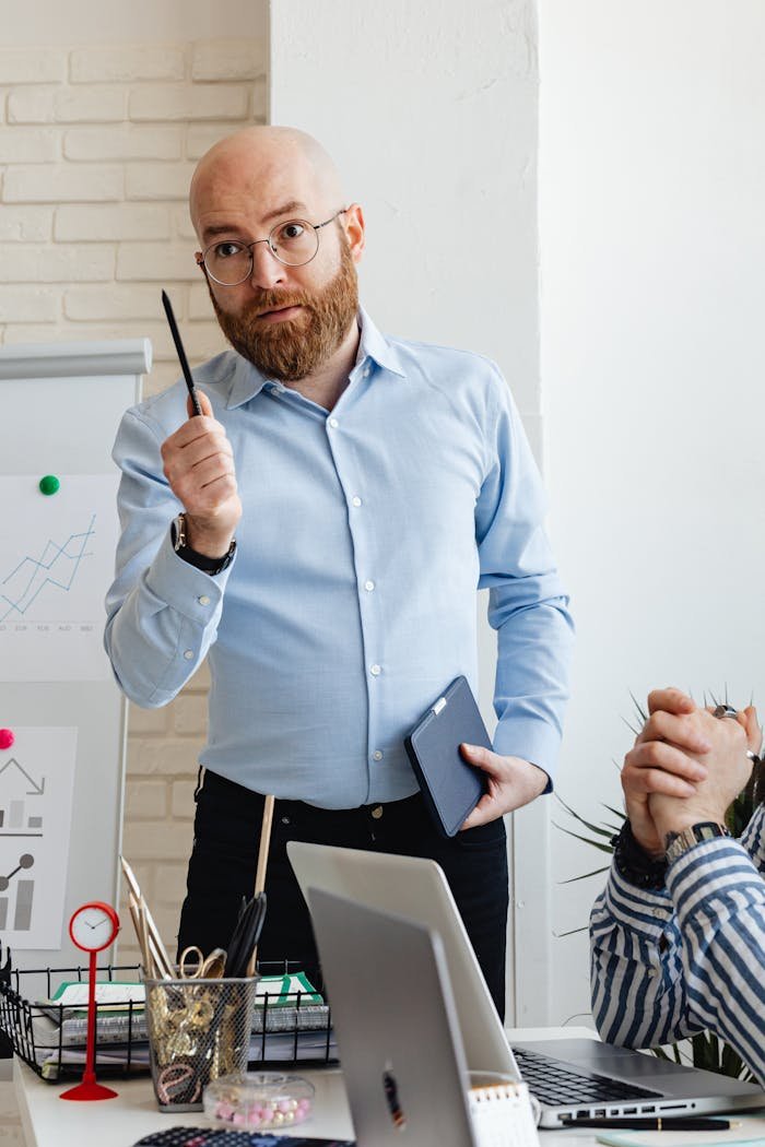 our-story Bald businessman with beard giving a presentation in a modern office setting.