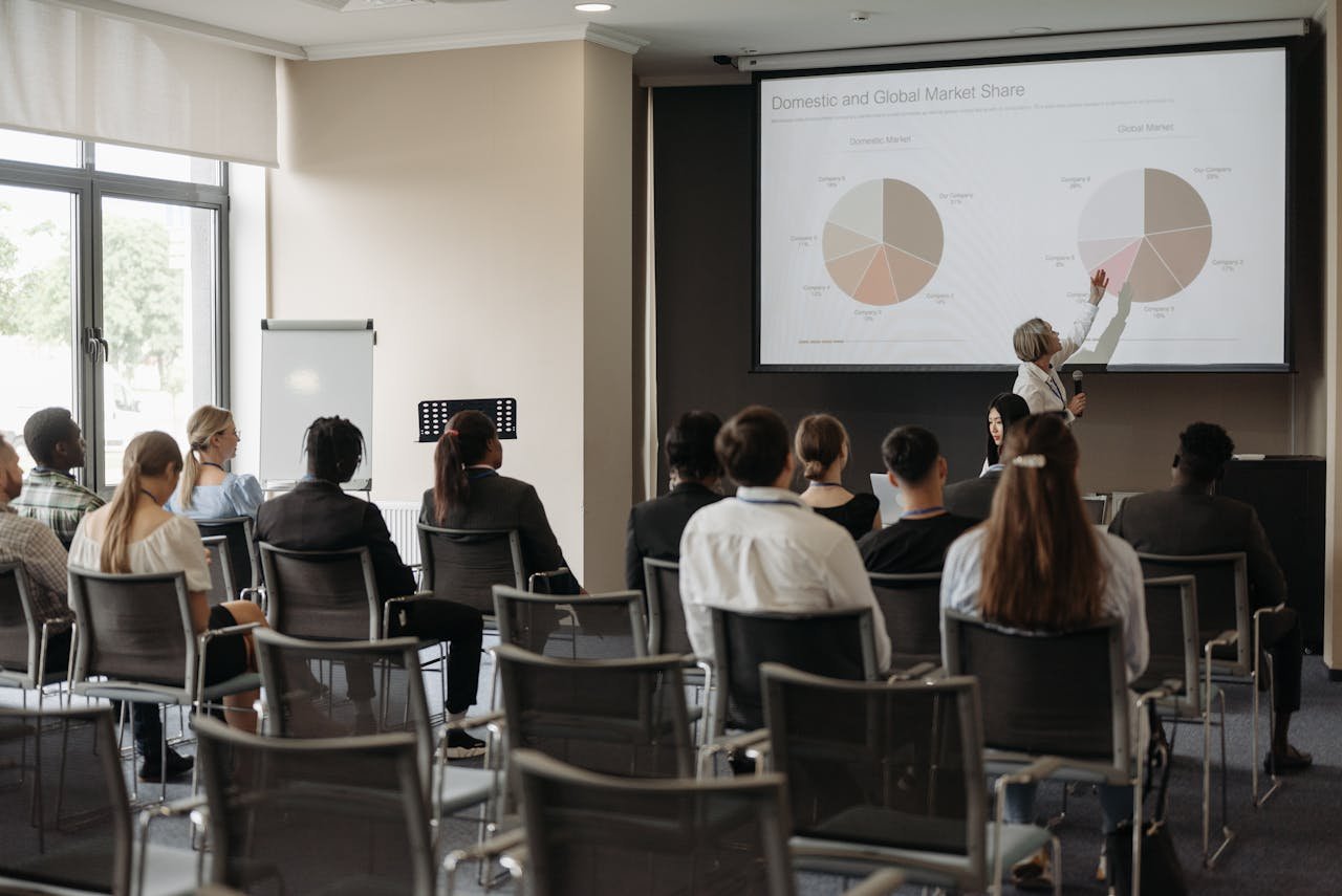 Business professionals attending a seminar with a presentation on market share, highlighting diverse participation.